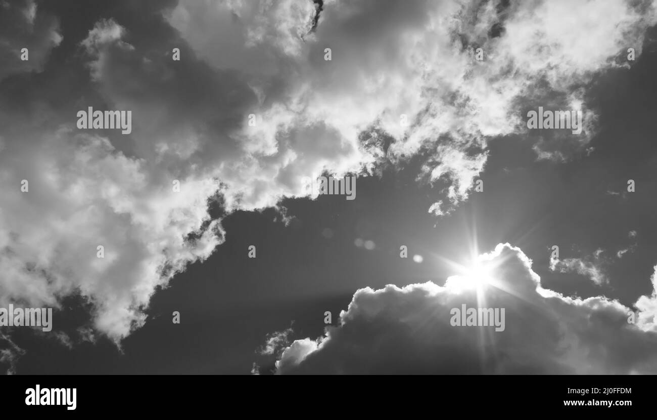 Am Himmel bricht die Sonne durch die Wolken. Schwarzweiß-Foto Stockfoto