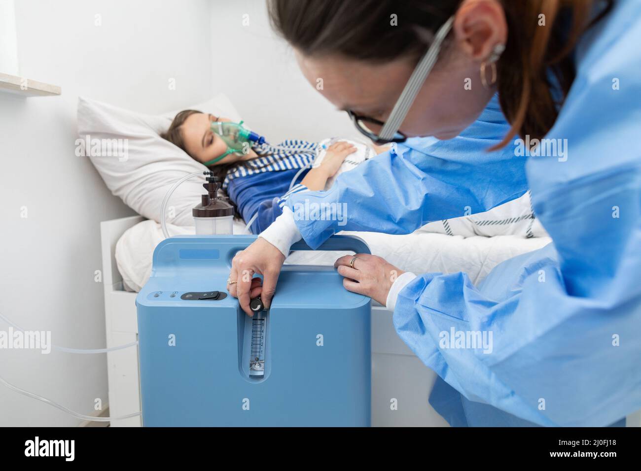 Der Arzt reguliert die Atemschutzmaske so, dass der Patient die richtige Menge an Sauerstoff hat. Stockfoto