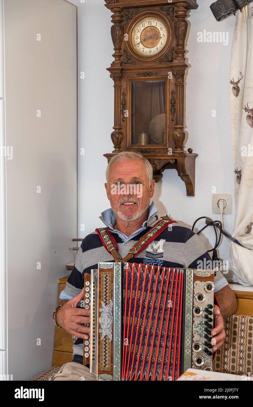 Musiker mit Akkordeon in einem alten Bauernzimmer Stockfoto