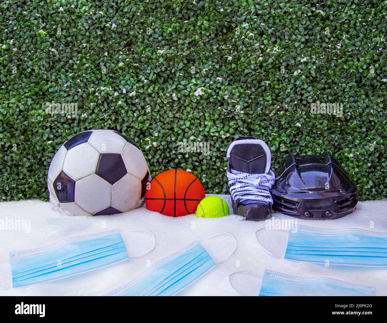 Ein Fußball oder Fußball, Basketball, Tennisball, Schlittschuhe mit Helm auf Schnee mit Gesichtsmasken. Konzept: Sport im Winter Stockfoto
