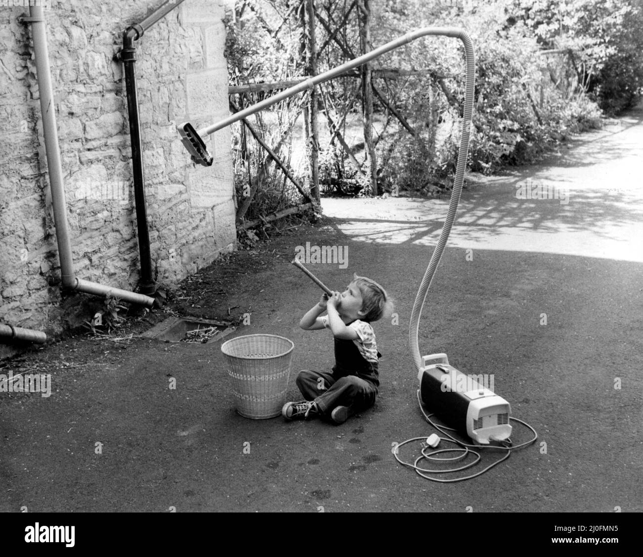 Ein Bild aus einer Serie humorvoller Neuheitenbilder, aufgenommen vom Sunday People-Fotografen Dennis Hutchinson. Dieser junge Bursche will Tricks machen wie die Zauberer, die er im Fernsehen sieht. ¿ sieht so aus, als ob er einen ¿schädigenden¿Job mit seiner Mutter macht¿ Hoover! Circa: 1980 Stockfoto