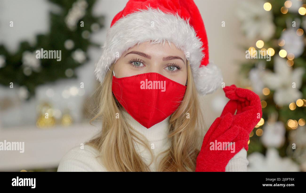 Porträt einer schönen Frau in weihnachtsmütze. Die Frau trägt die Schutzmaske des Virus Stockfoto