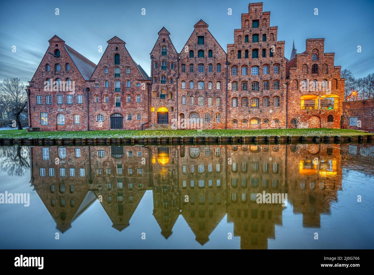 Der historische Salzspeicher spiegelt sich in der Trave bei Sonnenaufgang, gesehen in Lübeck, Deutschland Stockfoto