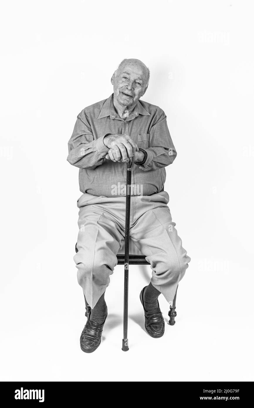 Gerne älterer Mann vor einem weißen Hintergrund sitzen Stockfoto