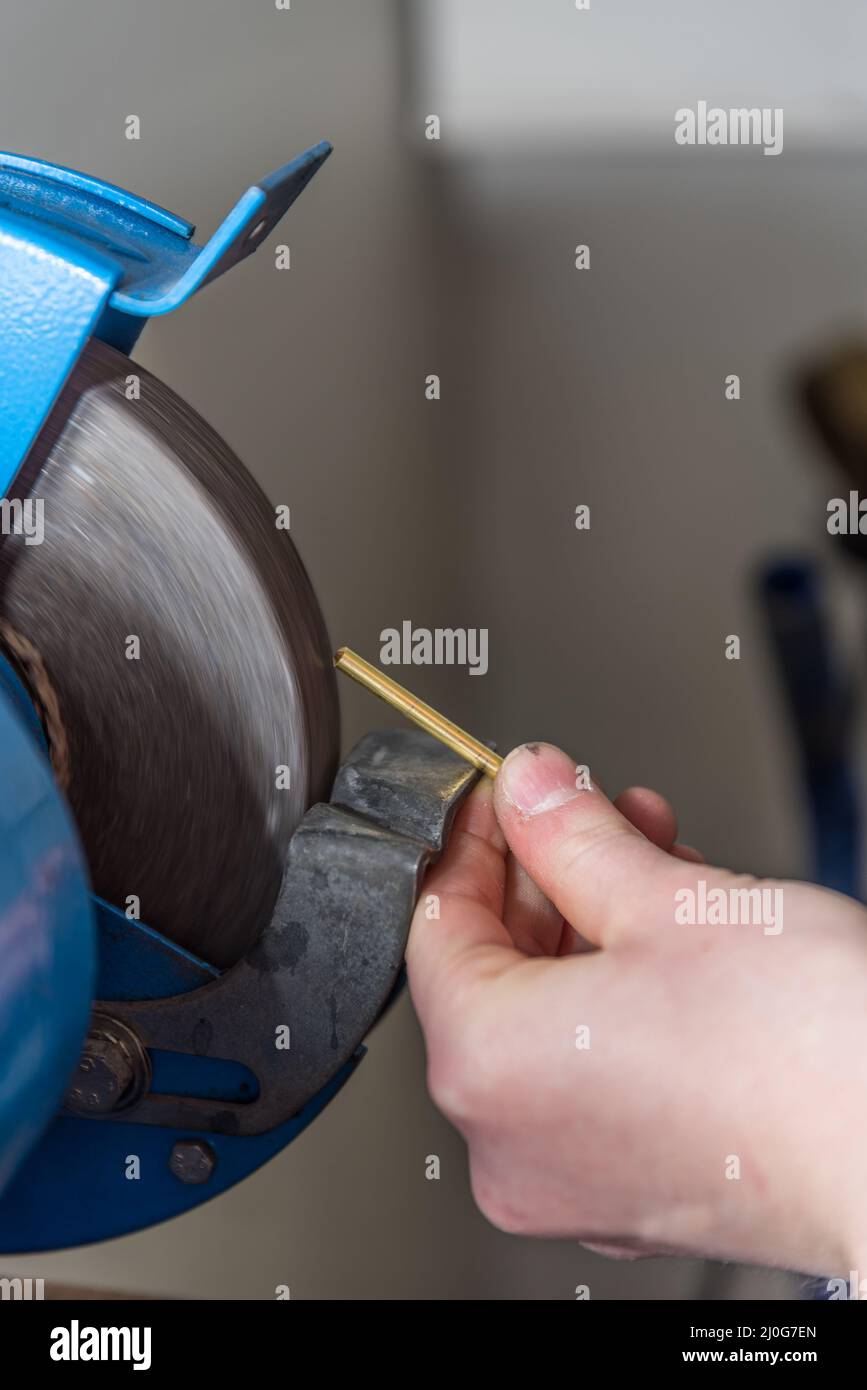 Metallarbeiter schleift mit der Trockenschleifmaschine - Nahaufnahme der Metallindustrie Stockfoto