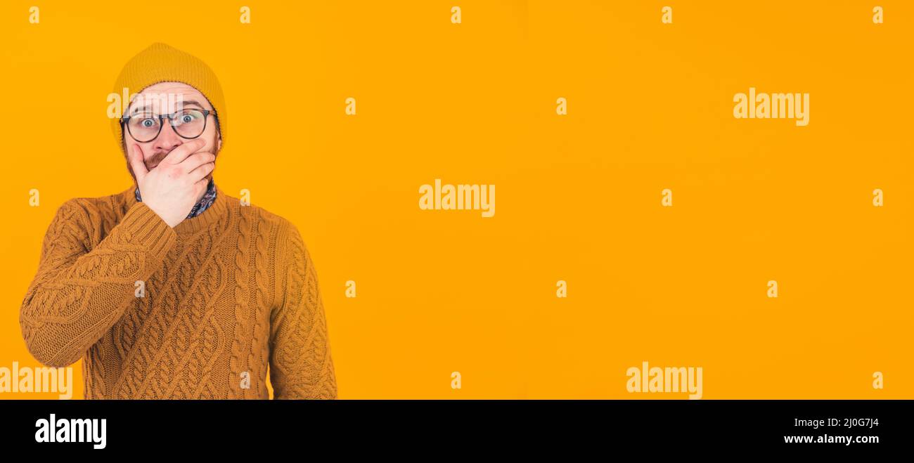 Erstaunt jungen kaukasischen Mann schließt seinen Mund mit einer Hand schockierende Nachrichten, attraktive Angebot Konzept Porträt orange Hintergrund kopieren Raum Studio isoliert geschossen . Hochwertige Fotos Stockfoto