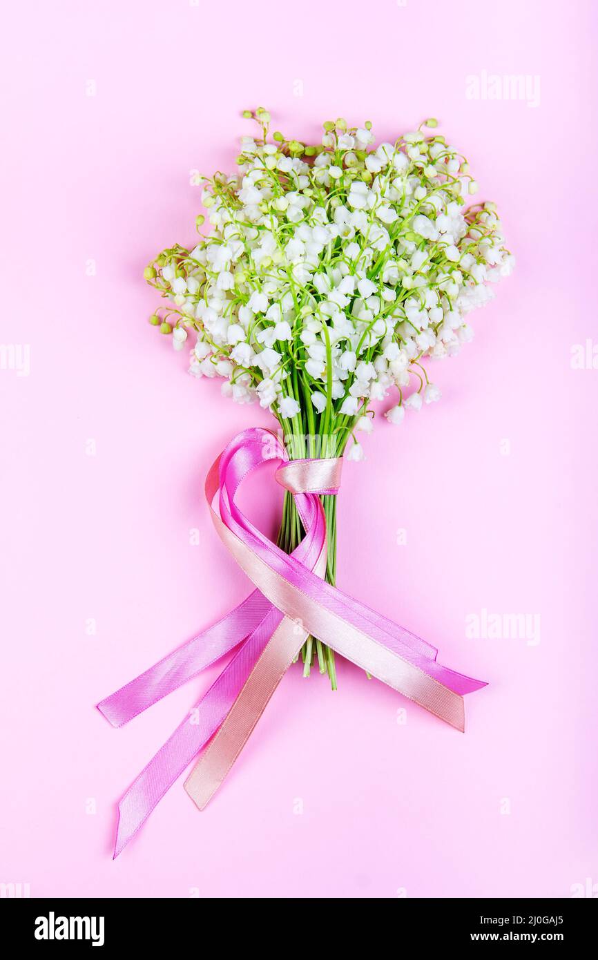 Bouquet von Maiglöckchen Blumen mit rosa Bändern auf einem rosa Hintergrund close-up Stockfoto