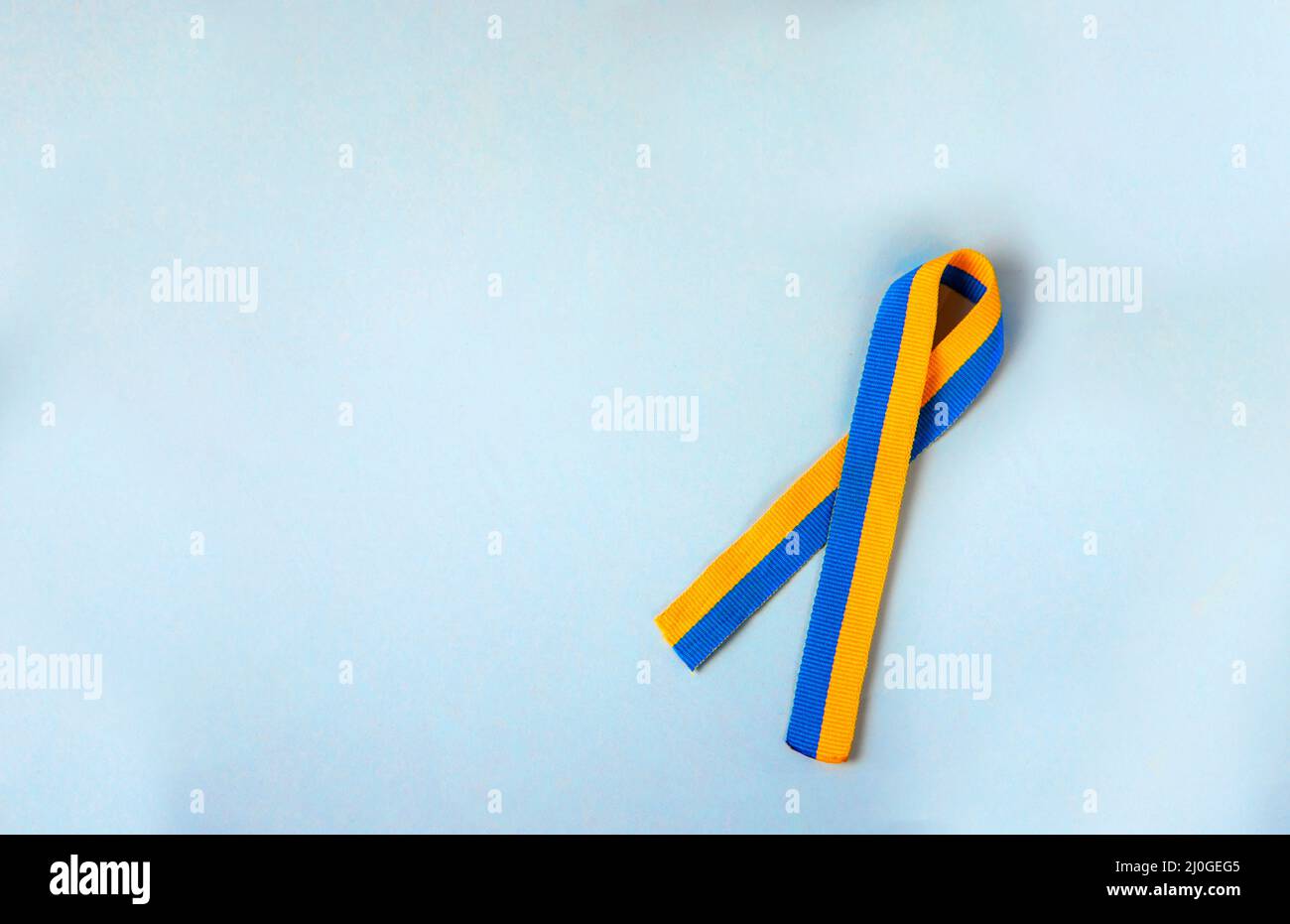 Gelb-blau (Farben der ukrainischen Flagge) symbolisches Band der Solidarität isoliert liegt auf einem hellblauen Hintergrund Stockfoto
