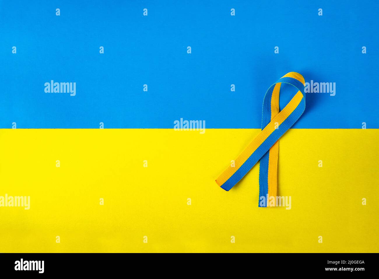 Gelb-blau (Farben der ukrainischen Flagge) symbolisches Band der Solidarität isoliert liegt auf einem gelb-blauen Hintergrund Stockfoto