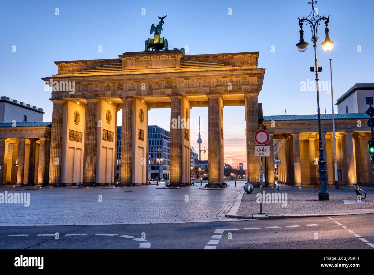 Das Brandenburger Tor mit dem Fernsehturm im Hintergrund bei Sonnenaufgang, gesehen in Berlin, Deutschland Stockfoto