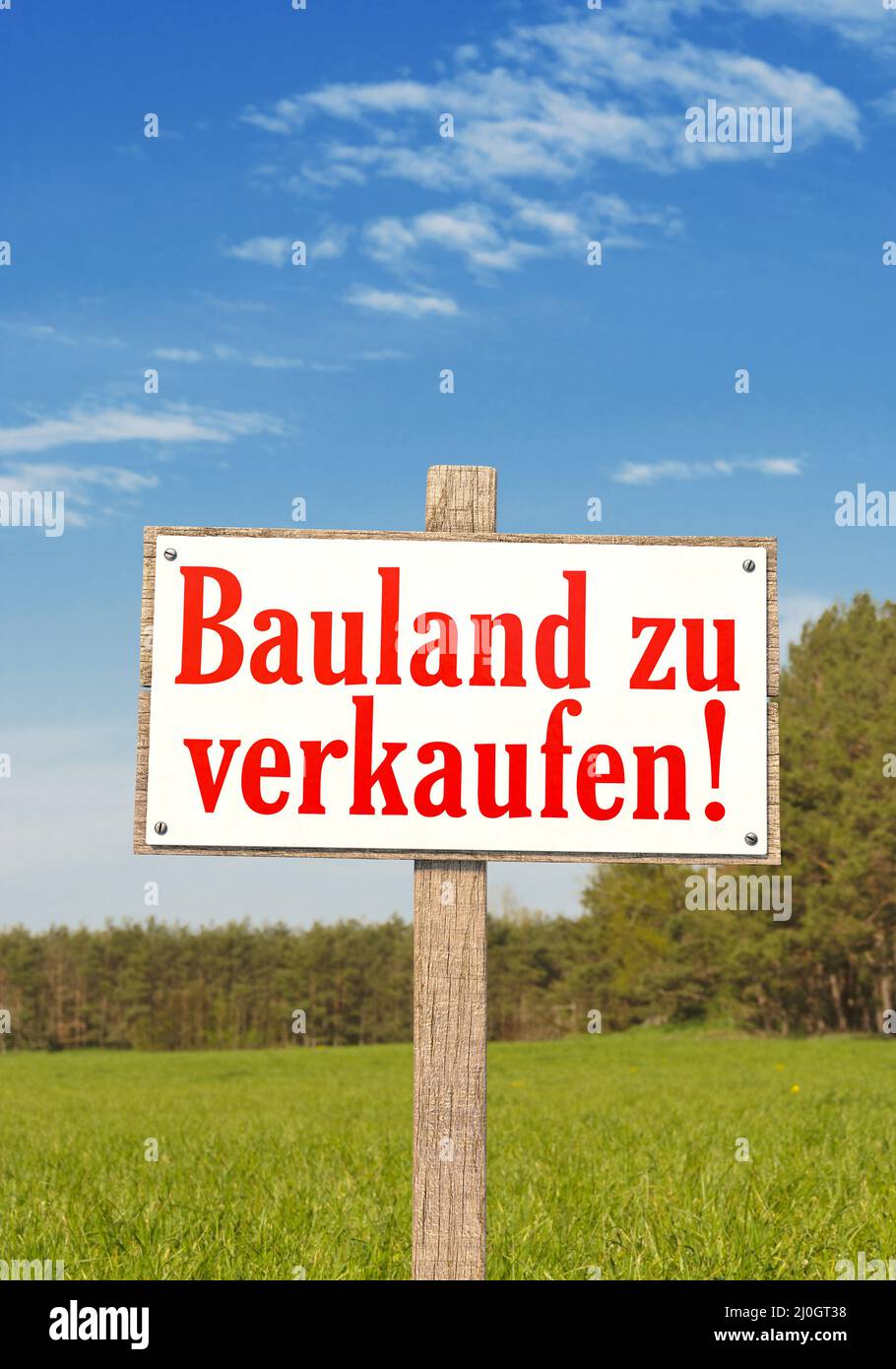Schild auf einem grünen Feld mit dem deutschen Text: Bauland zu verkaufen In po Stockfoto