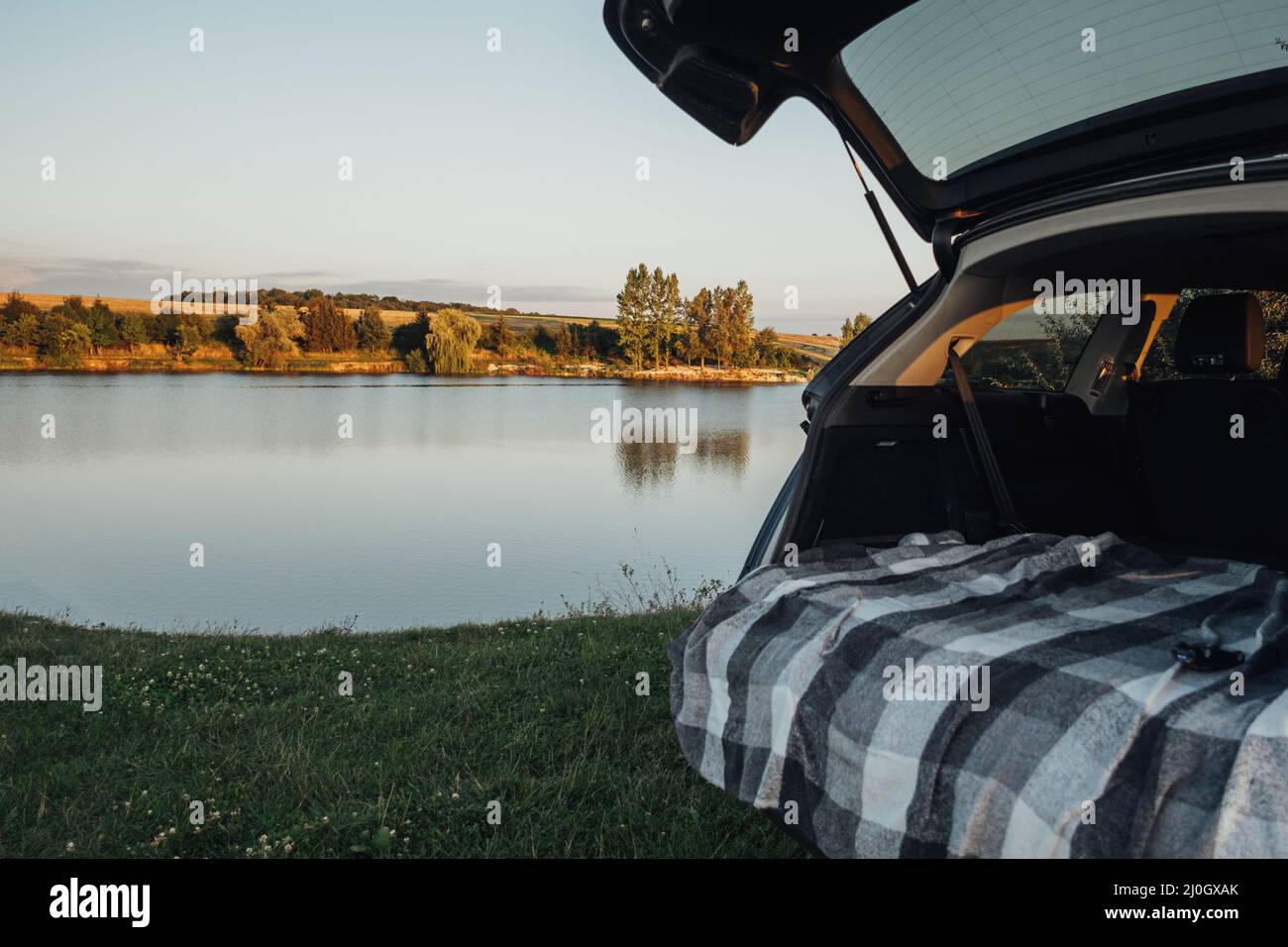 Offener Kofferraum des SUV-Fahrzeugs auf dem Hintergrund des Country Lake, Road Trip Concept Stockfoto