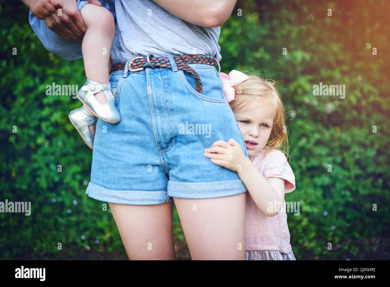 Probleme beim Loslassen. Aufnahme eines kleinen Mädchens, das während eines Tages im Freien an ihrer Mutter festhält. Stockfoto