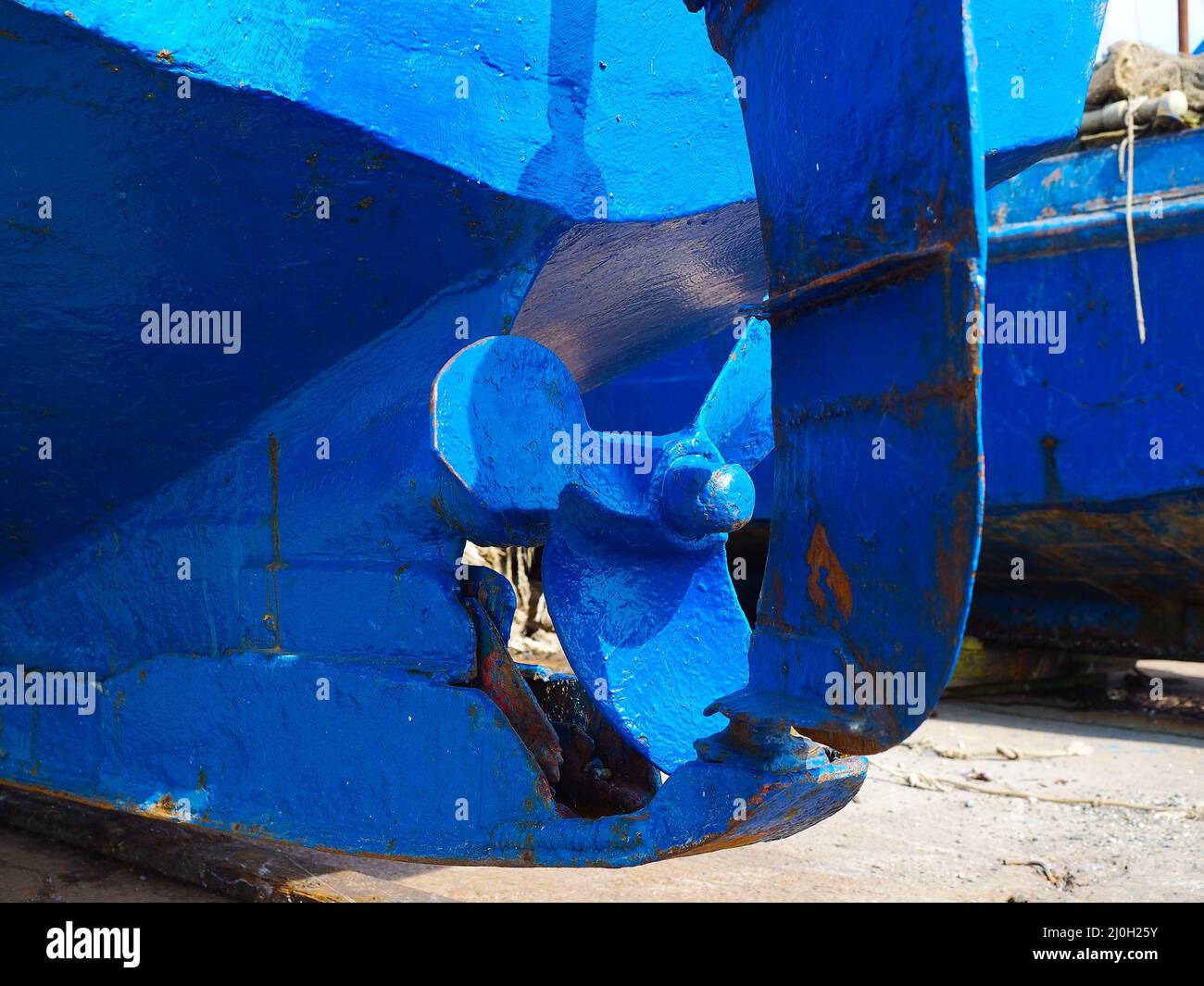 Der Propeller eines alten, blau rostigen Schiffes, das an einem sonnigen Tag auf trockenem Land steht Stockfoto
