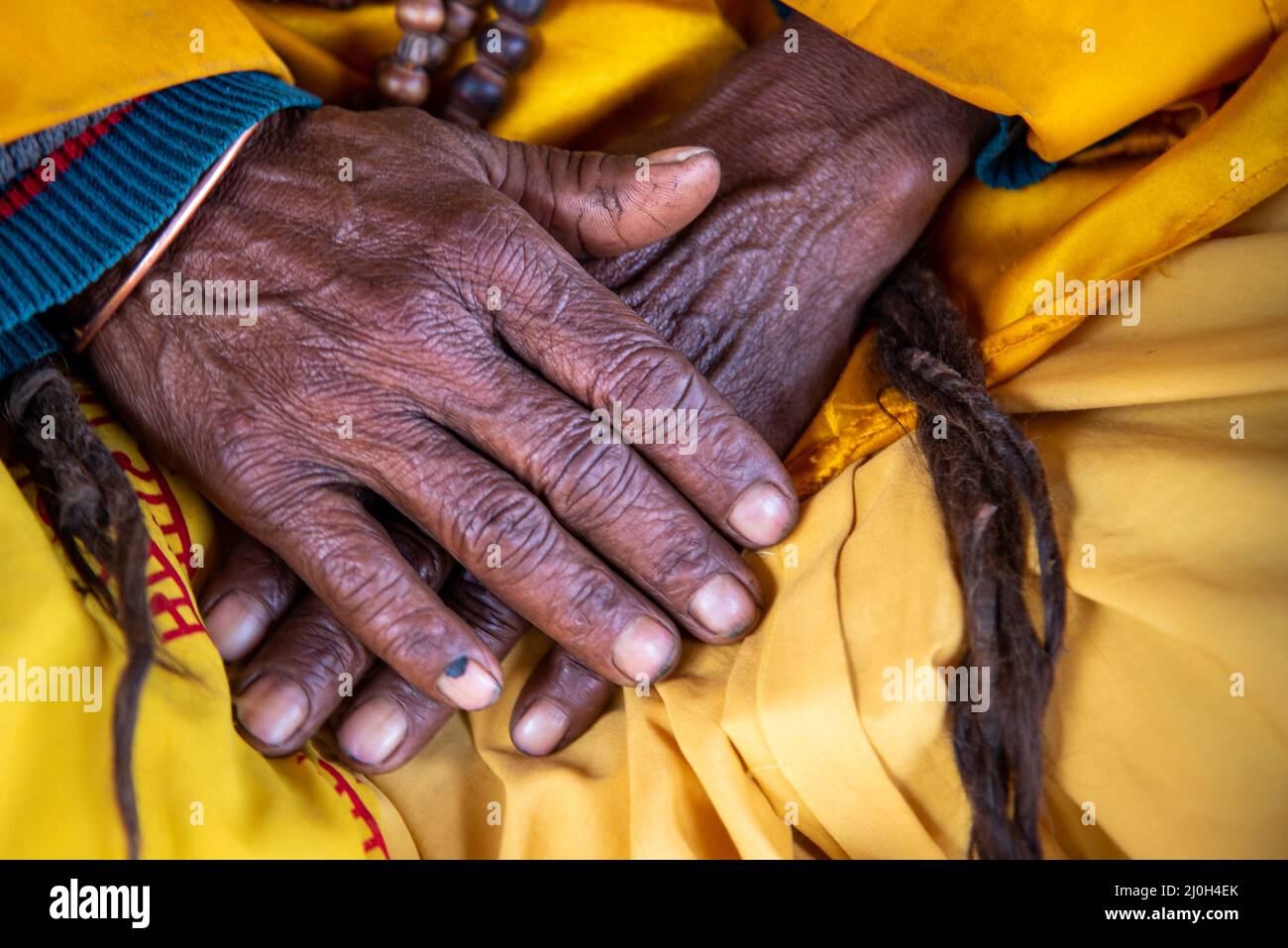 Nahaufnahme der gekreuzten faltigen Hände einer älteren Großmutter, einer nepalesischen Frau. Stockfoto
