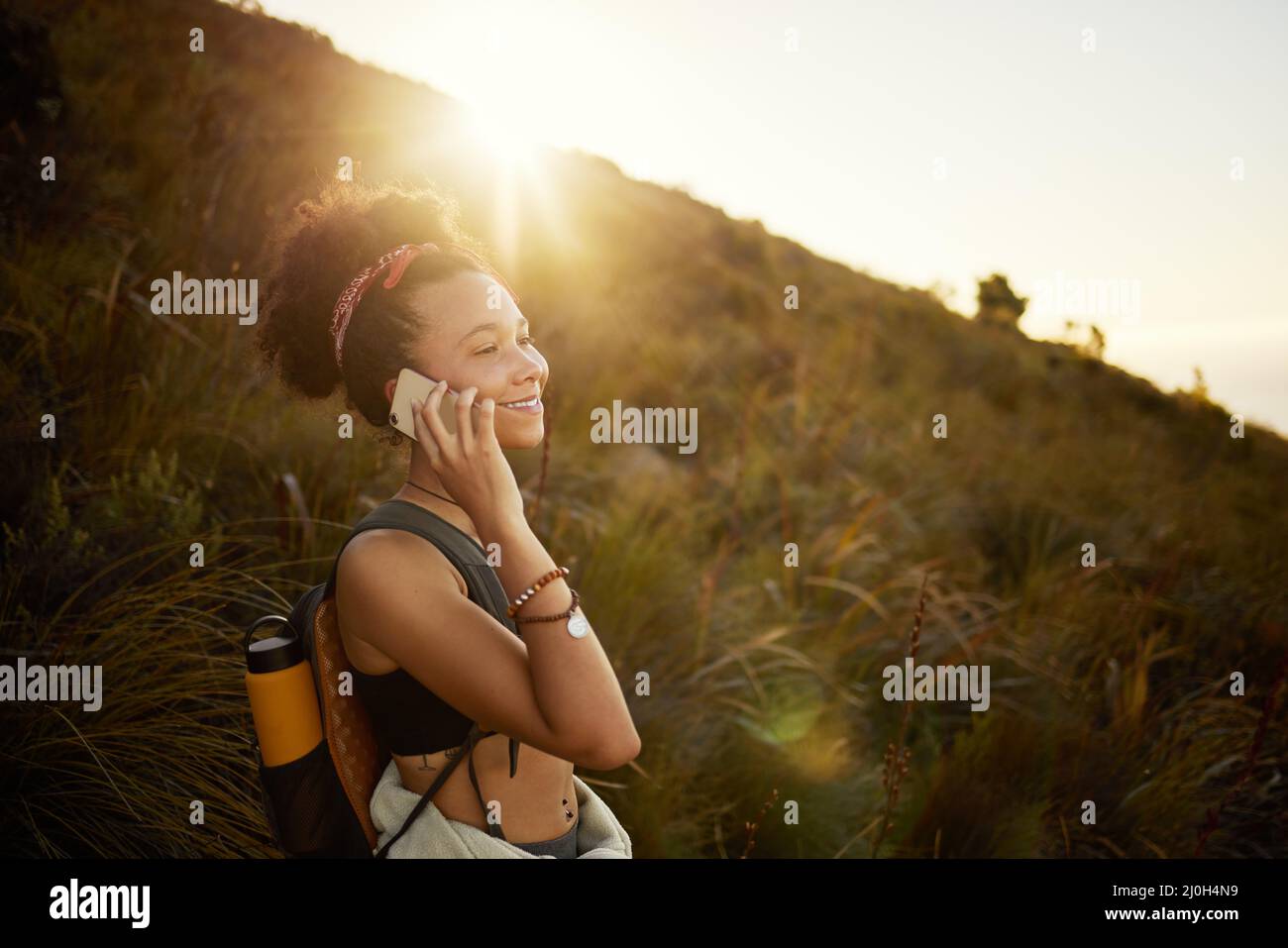 Tut mir leid, ich habe Ihren Anruf verpasst, ich bin unterwegs. Aufnahme einer jungen Frau, die beim Wandern auf ihrem Handy spricht. Stockfoto