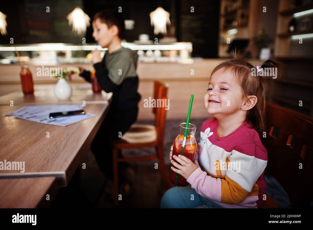 Lustige Baby Mädchen im Café sitzen und Saft Limonade trinken. Stockfoto