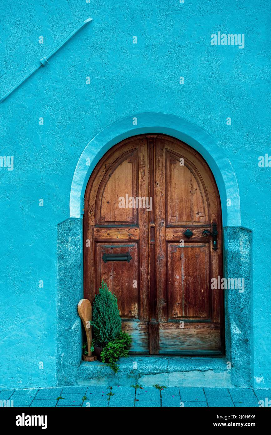 Alte rötlich-braune Holztür an der blauen Wand. Stockfoto