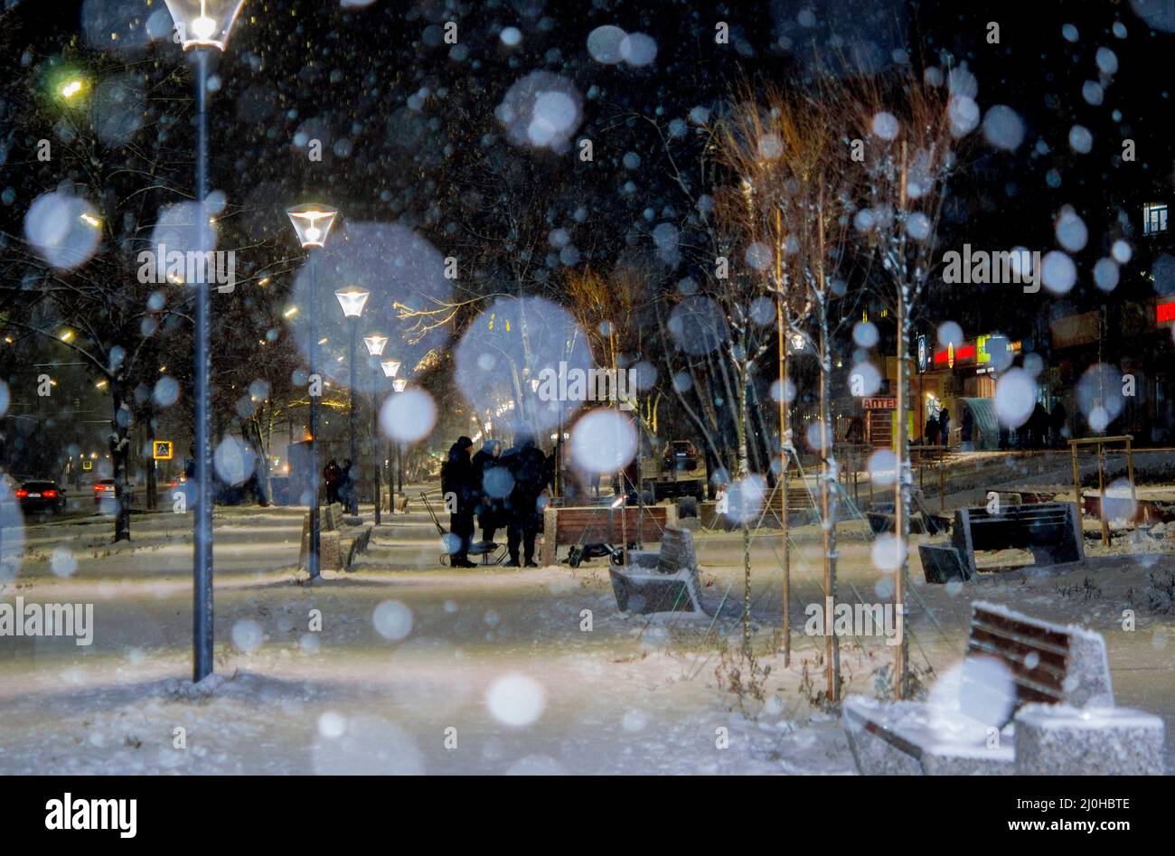 Blick auf die Stadt, Lichter, fallender Schnee, Nacht, Straße, Bokeh-Punkte Stockfoto