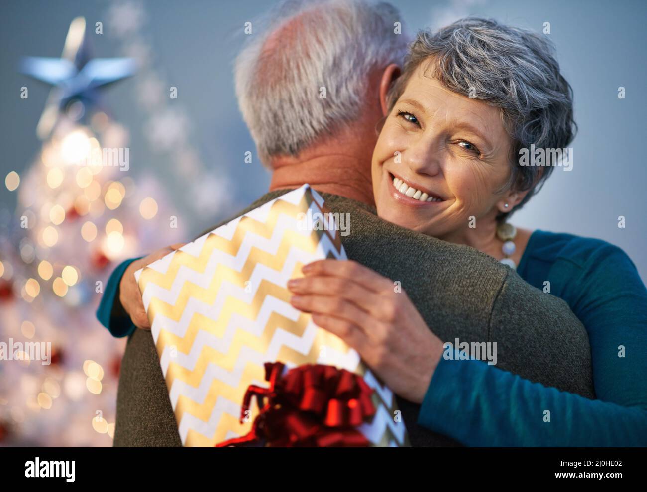 Weihnachtsumarmungen sind ihr eigenes Geschenk. Aufnahme einer reifen Frau, die ihren Partner umarmt, um ihm für ihr Geschenk zu danken. Stockfoto