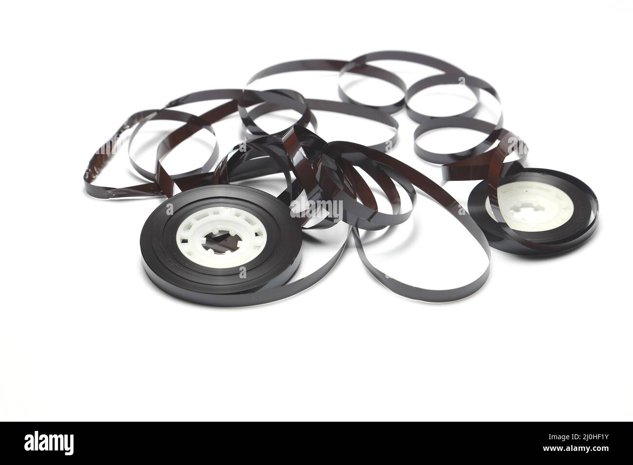 Alte Kassette mit aufgewickeltes Klebeband. Beschädigtes Datenträger für alte Tonaufnahmegeräte. Weißer Hintergrund. Stücke von einem alten Vintage-Kassettenband Stockfoto