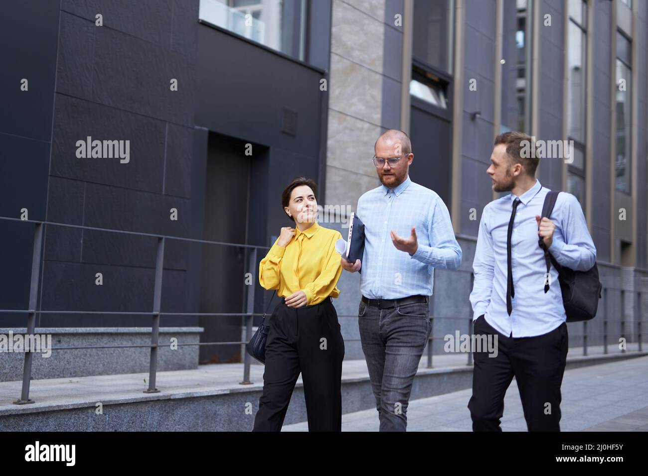 Geschäftsleute im Freien. Drei Angestellte in formeller Kleidung, die während der Büropause die Straße entlang gehen, urbaner Hintergrund. Brainstorming oder Besprechung des Projekts. Hochwertige Fotos Stockfoto