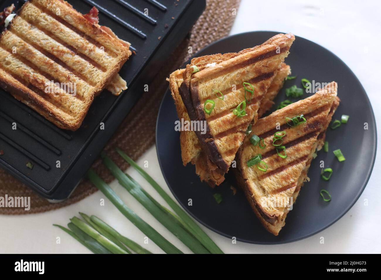 Sandwiches mit Frischkäse und Speck. Gegrillte Sandwiches mit einer Aufstrich aus einer Kombination aus Frischkäse, grünen Zwiebeln, Orangano und Chili Flocken. Schuss mit Witz Stockfoto