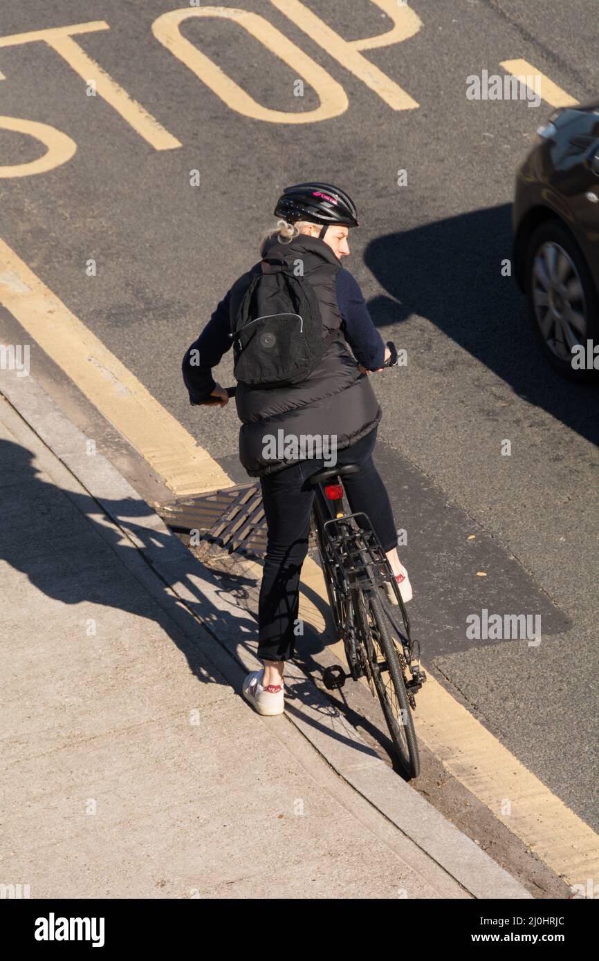 Eine Radfahrerin, die sich von der Bordsteinkante in den Straßenverkehr zieht Stockfoto