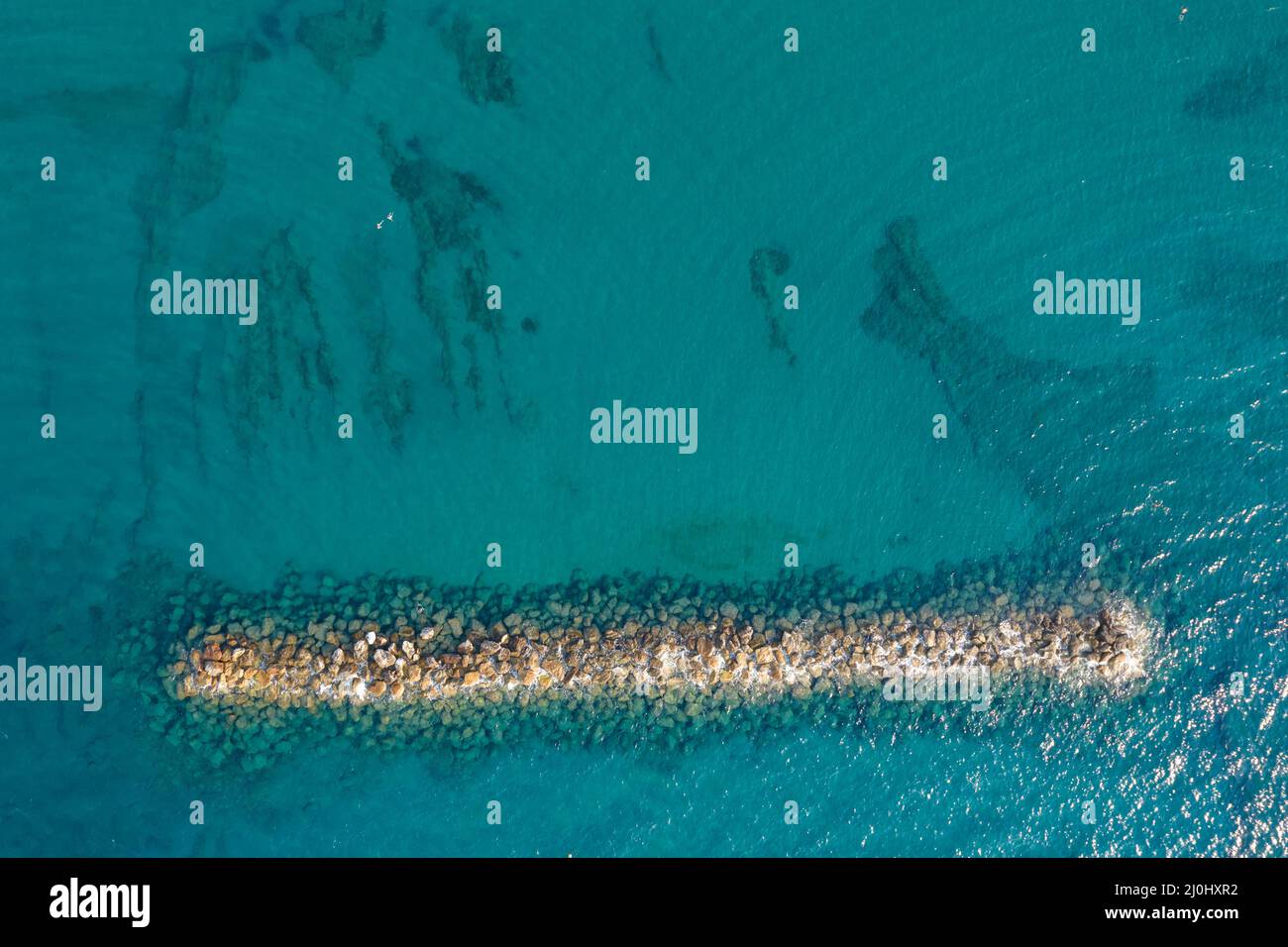 Luftaufnahme von einer fliegenden Drohne aus blauem Meerwasser und Wellenbrecher. Stockfoto