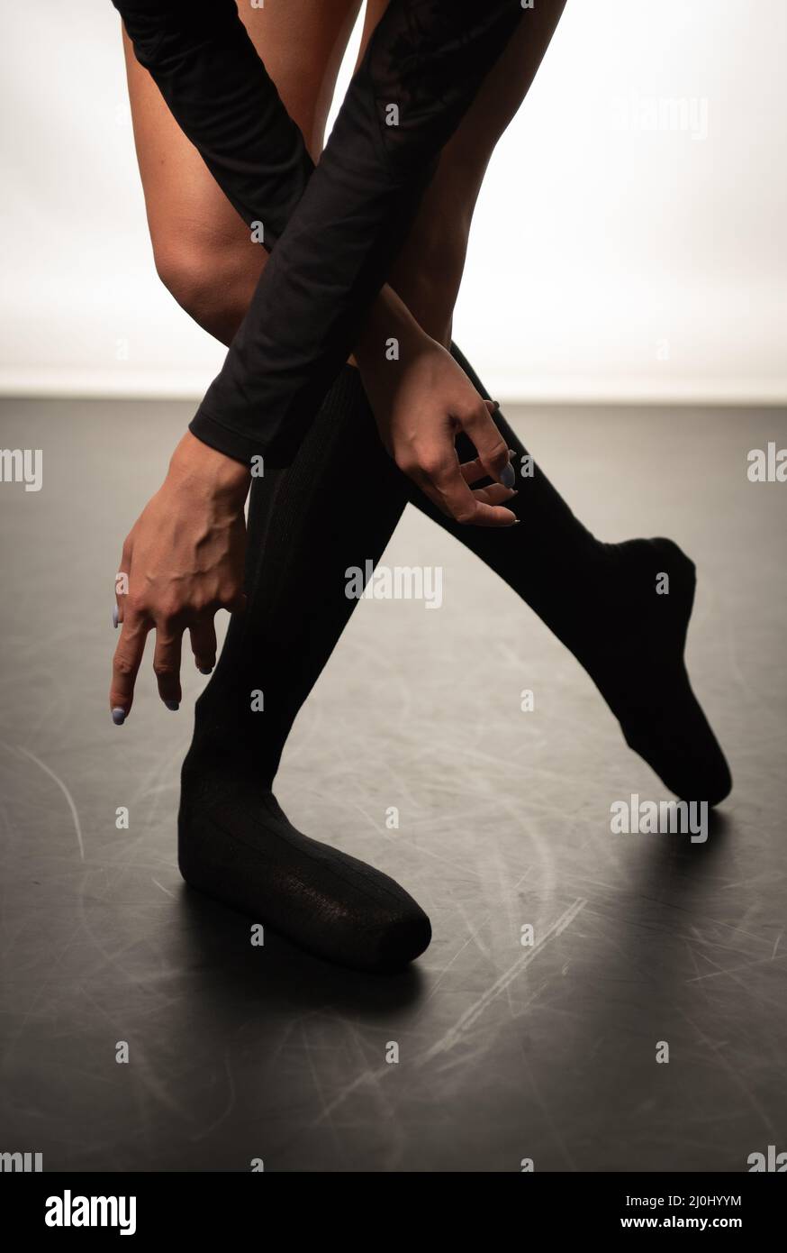 Beine einer jungen Ballerina mit spitzenschuhen, die auf einem schwarzen Boden tanzen. Ballettübung. Füße der Balletttänzerin. Stockfoto