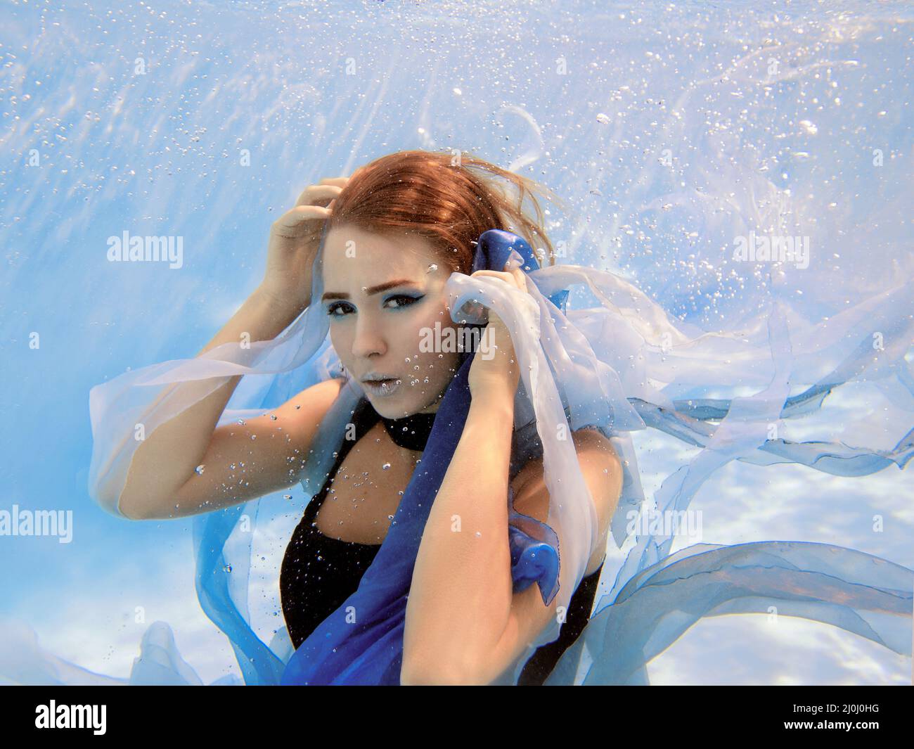 Unterwasser Mode Porträt der schönen jungen Frau in blauem Kleid Stockfoto