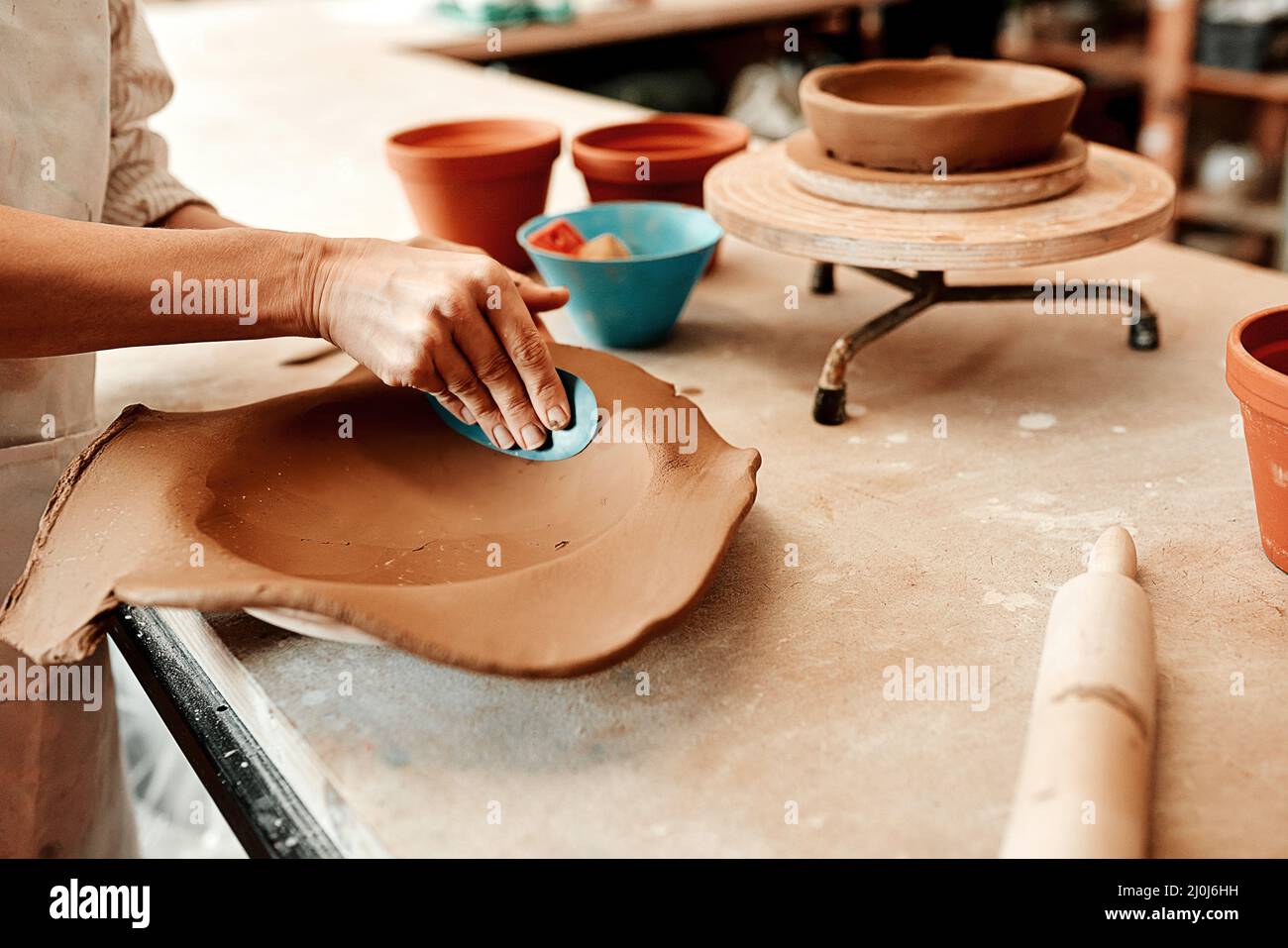 Ich muss es zuerst glätten. Ausgeschnittene Aufnahme eines nicht erkennbaren Handwerkers, der in einer Töpferwerkstatt arbeitet. Stockfoto