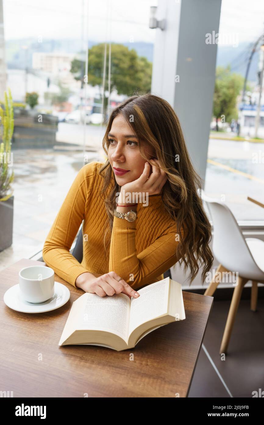 Schöne junge latina mit langen blonden Haaren sitzen, während eine Tasse Kaffee und lesen Sie ein Buch, Lifestyle und intellektuelle Hobby, Schönheit Stockfoto