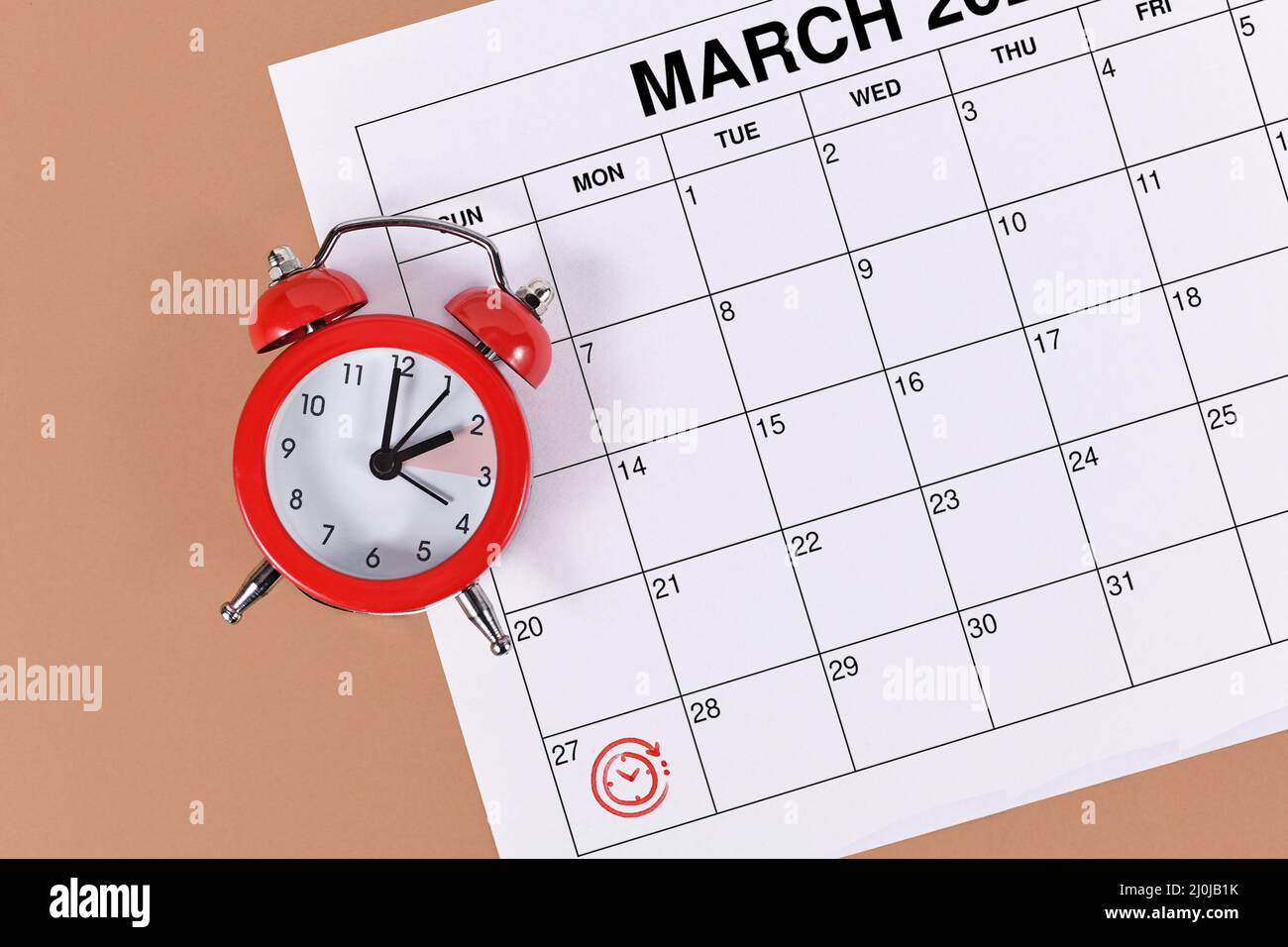 Konzept für den Zeitwechsel für die mitteleuropäische Sommerzeit am 27.. März mit rotem Wecker und Kalenderblatt Stockfoto