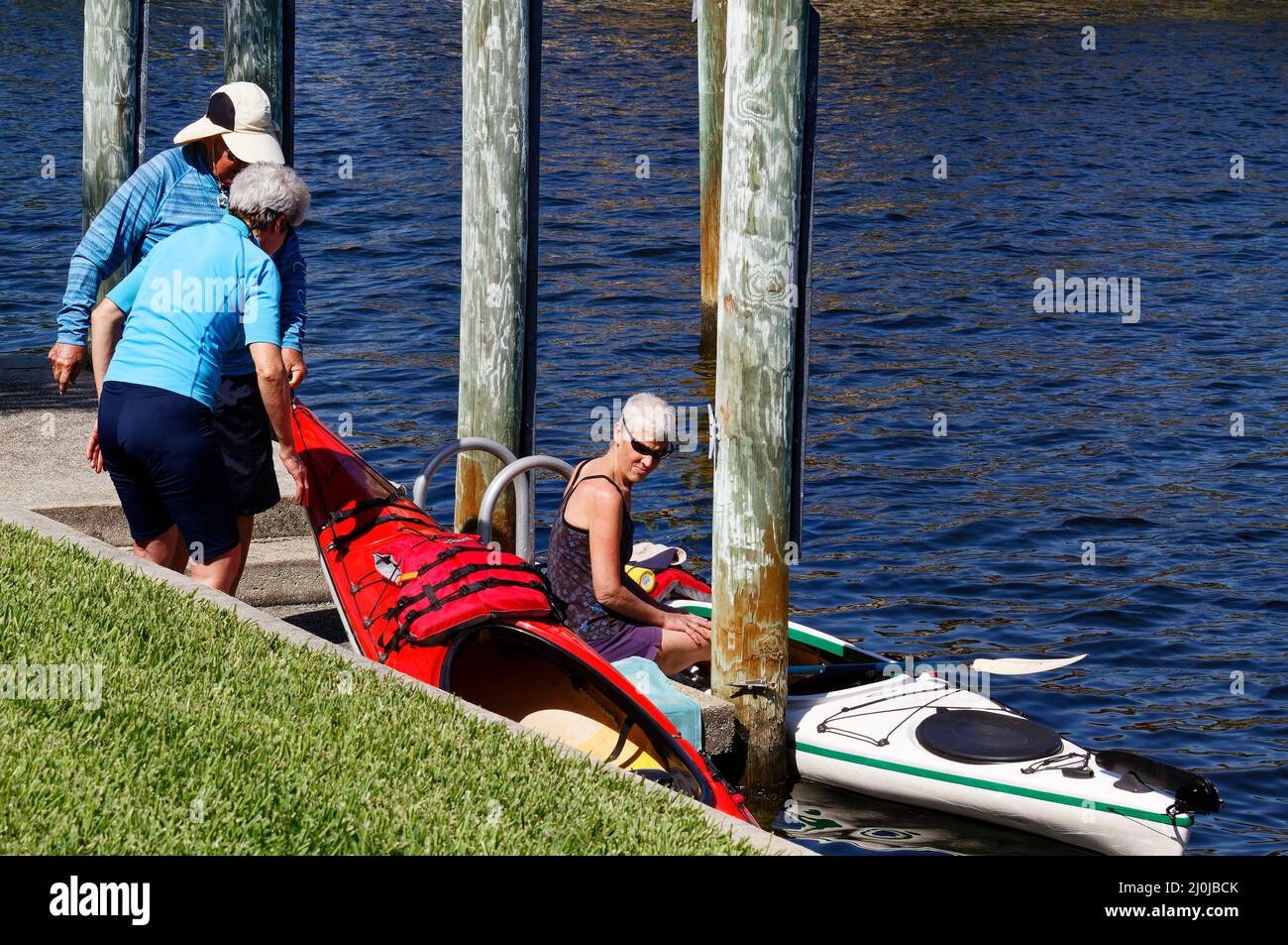 3 Personen, die Kajaks ins Wasser legen, Dock, Sport, Erholung, Spaß, Übung, Florida, Punta Gorda, FL, MR Stockfoto