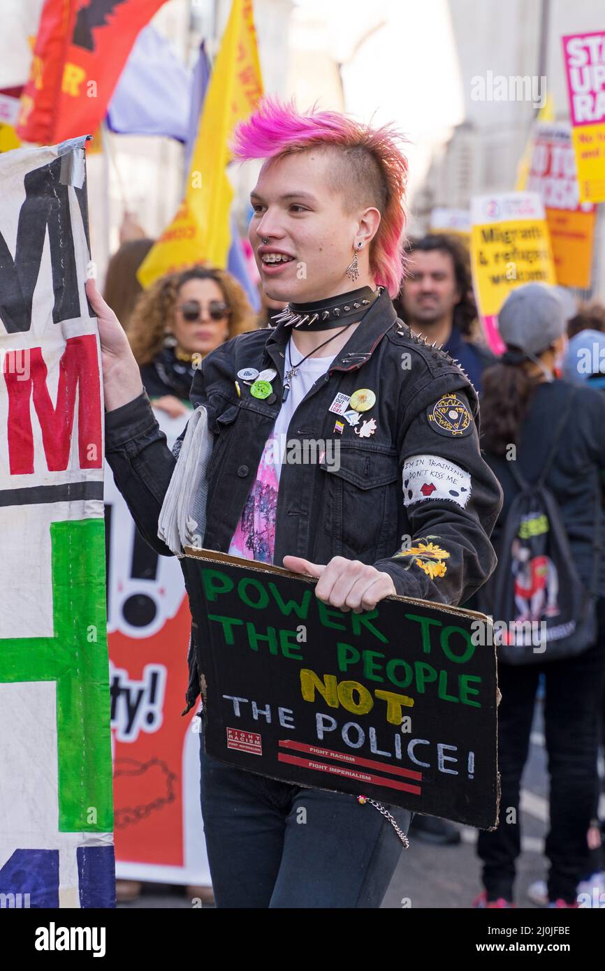 Anti-Rassismus-Protest auf den Straßen von London. Ein Protestor mit pinkfarbenem Haarschnitt im Punk-Stil, der ein Banner hält. London - 19.. März 2022 Stockfoto