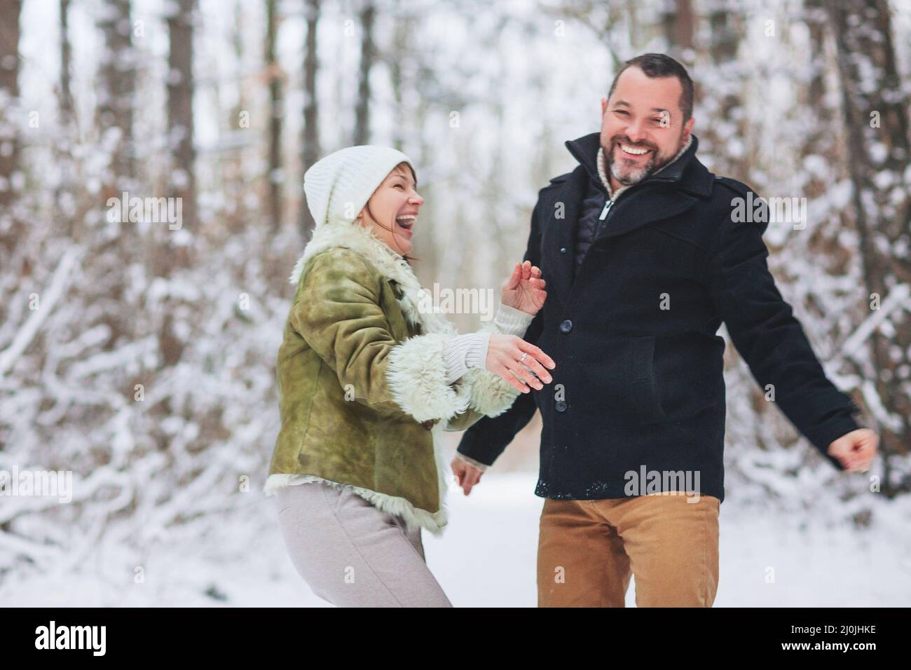 Schönes, glückliches Familienpaar mittleren Alters, das in der Wintersaison gemeinsam Spaß im Freien hat Stockfoto