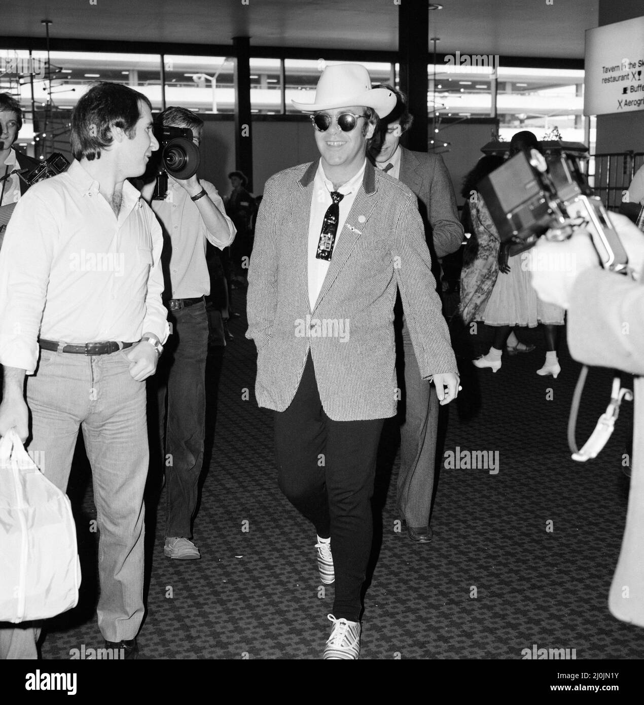 Mit einem stetson-Hut bekleidet verlässt Elton John den Flughafen Heathrow nach Amerika. 10.. August 1980. Stockfoto