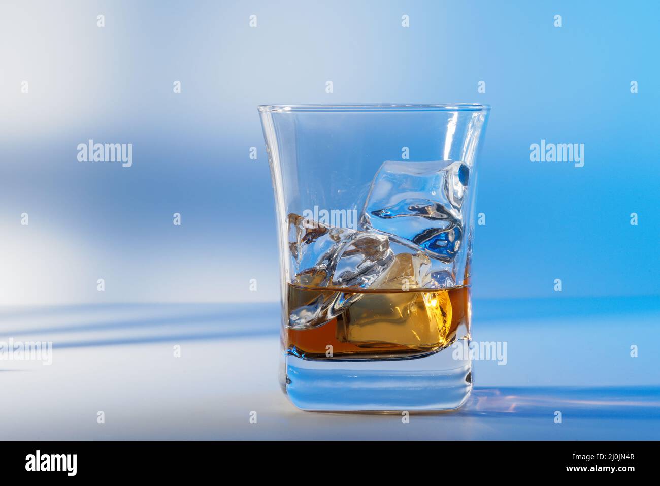 Ein Glas bernsteinfarbenem Scotch-Whiskey und Eis auf einem hellen Hintergrund Stockfoto