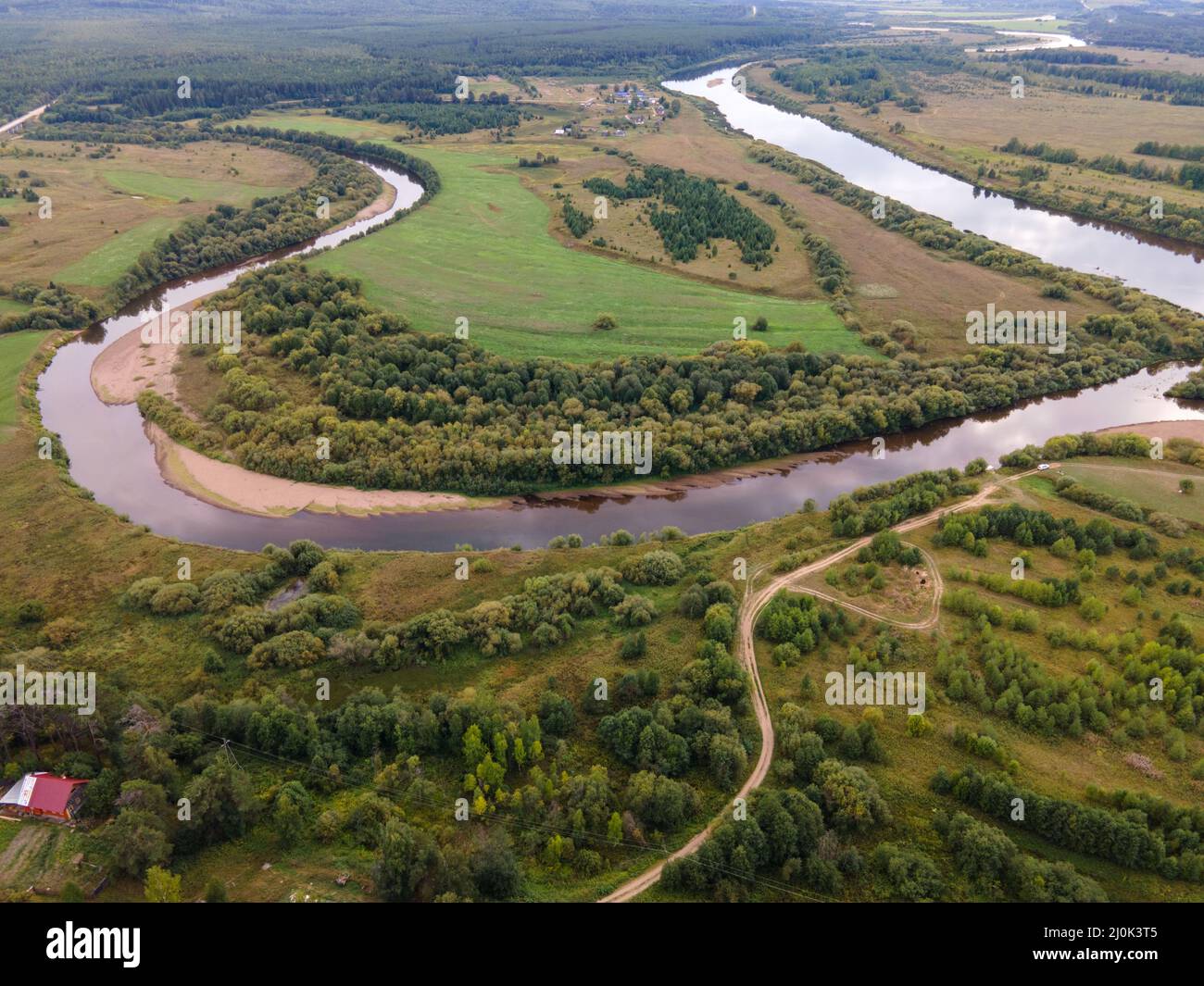 Fluss zwischen welliger Straße und Rasen mit Bäumen auf dem Land Stockfoto