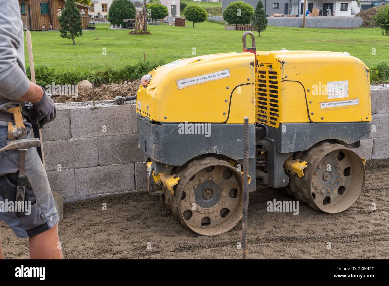 Bauarbeiter auf der Baustelle mit Grabenwalze, um den Erdbau zu verdichten - Hausbau Stockfoto