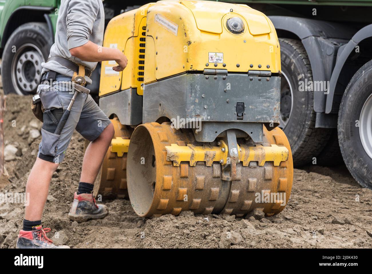 Bauarbeiter arbeitet mit Grabenwalze auf der Baustelle - Bauindustrie Stockfoto