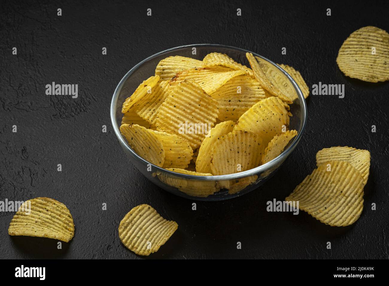 Geriffelte Kartoffelchips auf schwarzem Hintergrund Stockfoto
