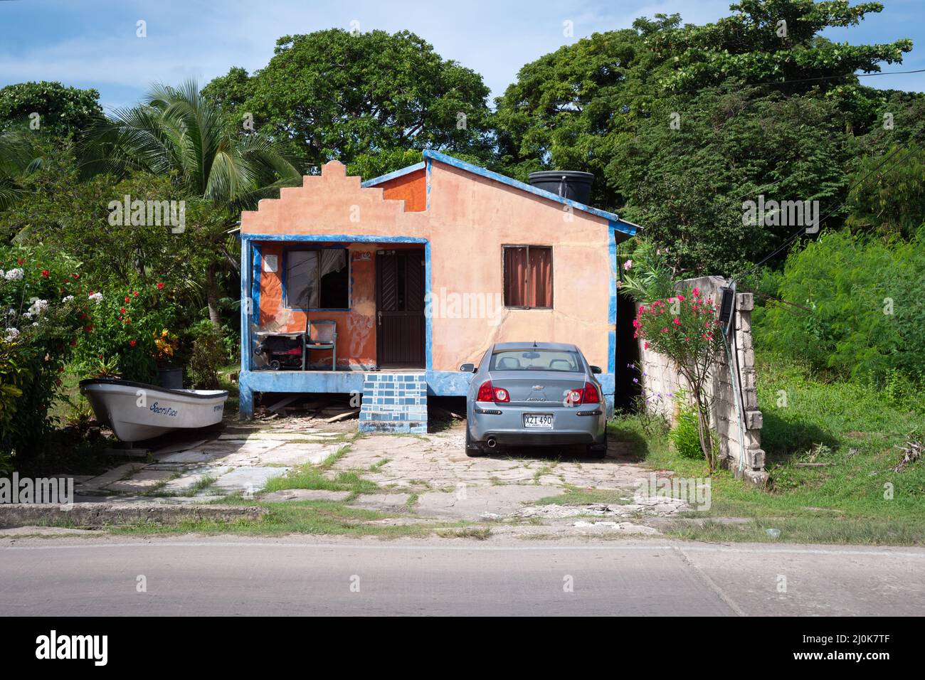 San Andrés, San Andrés y Providencia, Kolumbien - November 18 2021: Kleines Haus in weichem Orange mit einem Auto, das auf dem Hof in der Nähe eines Bootes geparkt ist Stockfoto