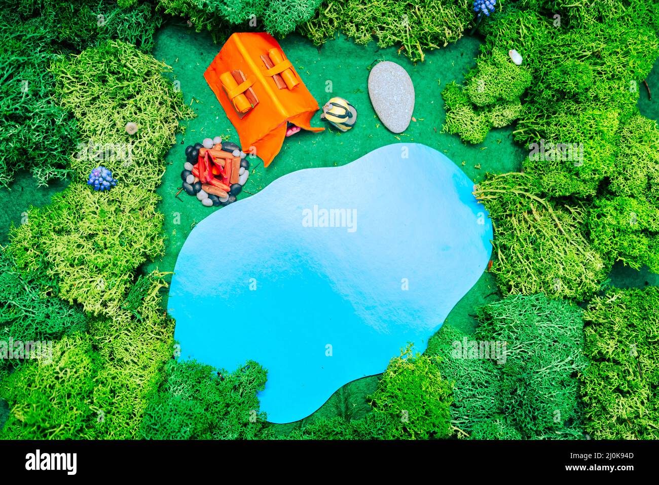 Plastilin-Landschaft mit Zelt, Feuer und Rucksack auf dem See. Blick von oben. Das Konzept der umweltfreundlichen Erholung und Umweltschutz Stockfoto