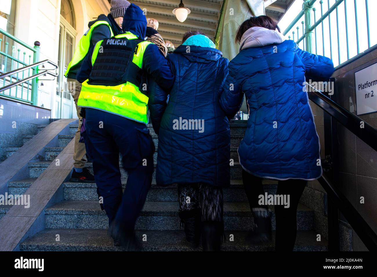 Przemysl, Ukraine. 18. März 2022. Ein polnischer Polizist hilft einer Frau auf einem polnischen Bahnhof eine Treppe hinauf. Ukrainische Flüchtlinge, die vor dem Krieg in ihrer Heimat fliehen, kommen im Zug nach Polen. (Foto von Ty O'Neil/SOPA Images/Sipa USA) Quelle: SIPA USA/Alamy Live News Stockfoto