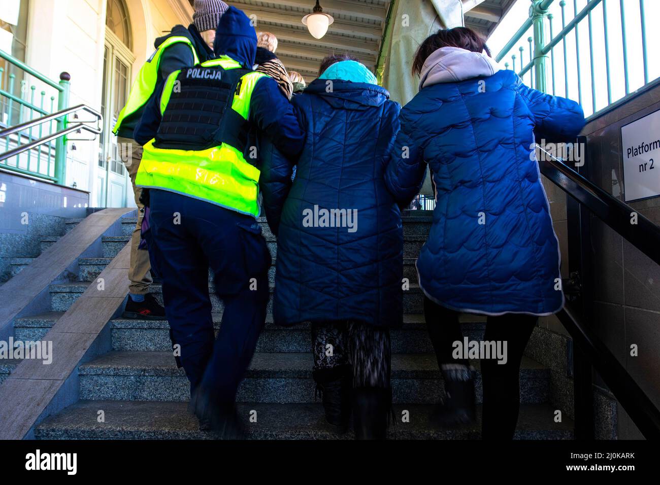 Przemysl, Ukraine. 18. März 2022. Ein polnischer Polizist hilft einer Frau auf einem polnischen Bahnhof eine Treppe hinauf. Ukrainische Flüchtlinge, die vor dem Krieg in ihrer Heimat fliehen, kommen im Zug nach Polen. (Bild: © Ty O'Neil/SOPA Images via ZUMA Press Wire) Stockfoto