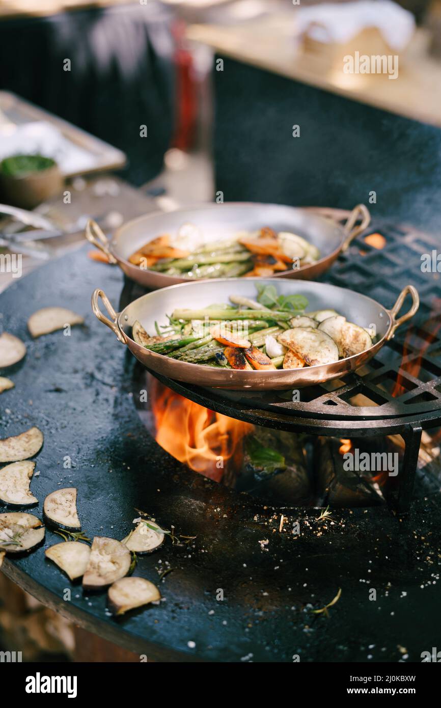 Gegrilltes Gemüse. - Spargel, Zucchini, Karotten und Auberginen gegrillte runde Schüssel mit offenem Feuer in der Mitte. Stockfoto