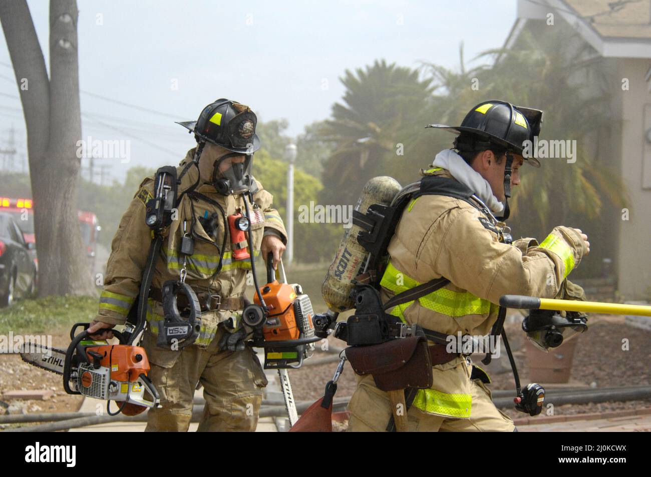 Die Feuerwehrleute der Stadt San Diego tragen die Ausrüstung zu einem Gebäude, das in Betrieb ist Stockfoto