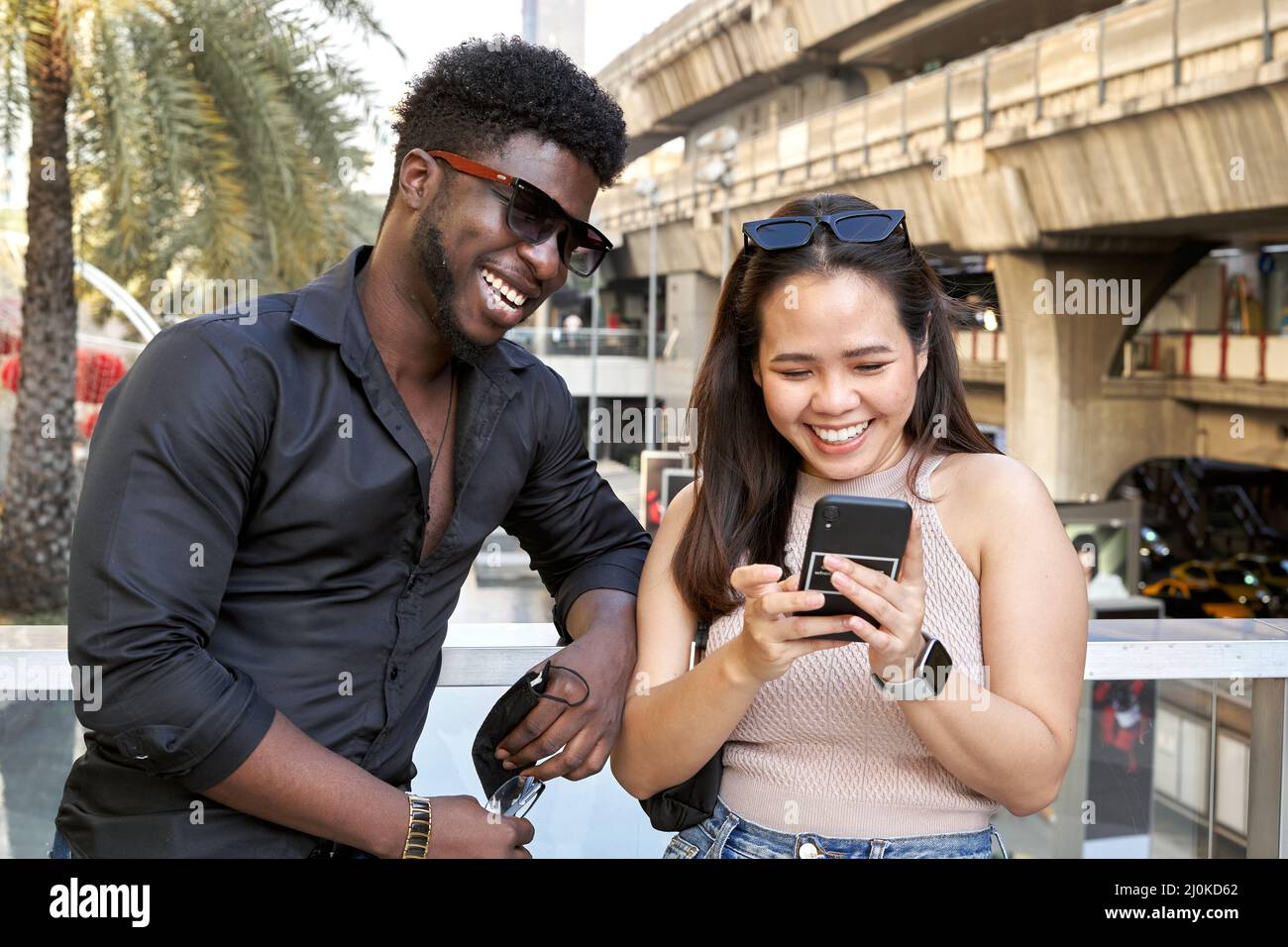Porträt zweier multiethnischer Freunde, die das Handy in einem Einkaufszentrum benutzen Stockfoto